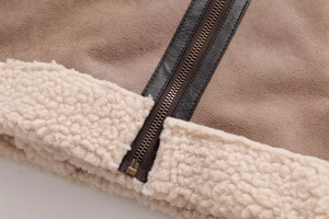 Close-up of brown suede jacket with cream faux shearling lining and bronze zipper detail