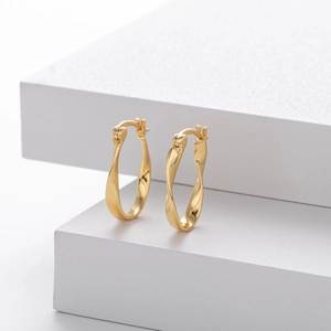 Elegant gold-tone 925 sterling silver Mobius twist hoop earrings on minimalist stone display