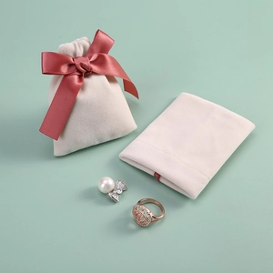 Elegant beige velvet drawstring jewelry pouch with pink satin bow and pearl earring