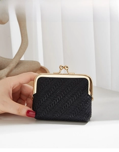 Close-up of black woven texture and golden metal clasp on a vintage coin purse