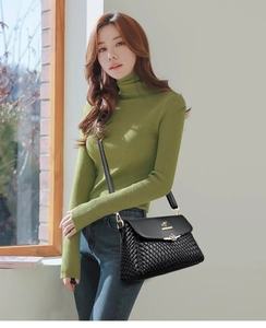 Close-up of black woven leather handbag with gold kangaroo emblem on a model