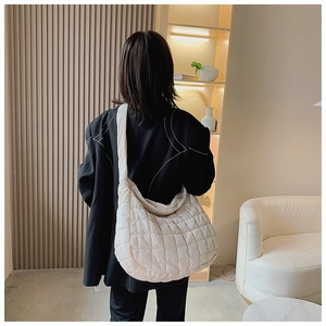 Sac nuage matelassé beige chic porté avec un blazer noir pour un look urbain