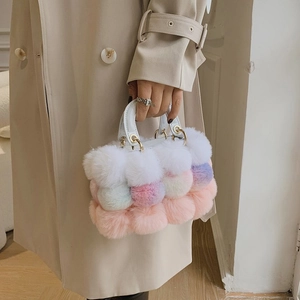 Detail of colorful fluffy pom-pom handbag with white leather handle and gold hardware