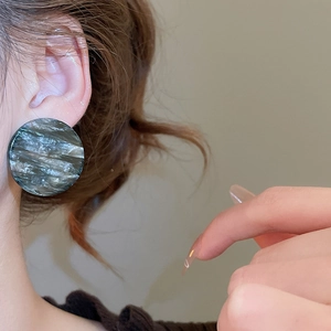 Gros plan de boucles d'oreilles géométriques en acrylique à texture marbre sombre