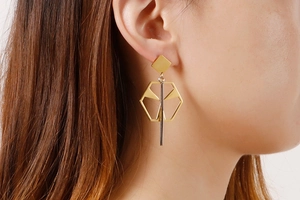 Detail of geometric titanium earrings with gold hexagon and silver vertical bar on model