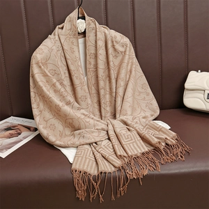 Dettaglio della sciarpa jacquard beige con motivi floreali e bordi greci su sfondo di pelle