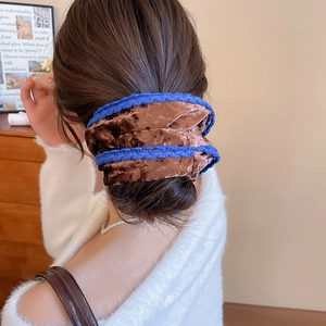 Brown velvet scrunchie with blue stitched edges worn in a stylish ponytail on model