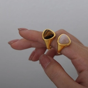 Close-up of gold-plated titanium steel rings with natural tiger eye and pink crystal stones