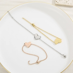 Trois bracelets cœur minimalistes en or, argent et or rose sur un plateau en céramique