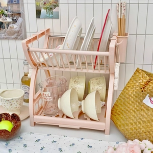 Pink 2-tier plastic dish drying rack with utensil holder in a modern kitchen setting