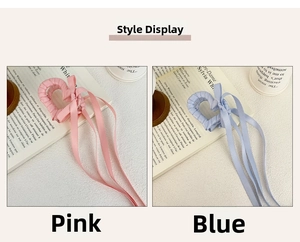 Dettaglio dei fermagli per capelli a cuore in raso rosa e blu con lunghi nastri eleganti