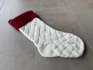 Close-up of white knit Christmas stocking with red ribbed cuff and hanging loop detail