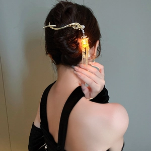 Detail of luminous lantern hair pin with gold dragon head and metallic tassels on hair