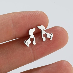 Close-up of small silver stainless steel puppy stud earrings held between fingers