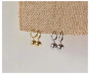 Detail von 14K Gold und S925 Silber Creolen mit Kugeln auf strukturiertem Stoff