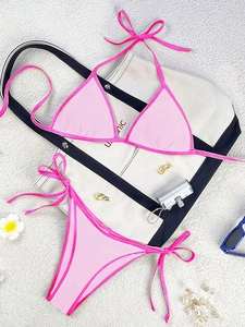 Flat lay of pink two-piece halter bikini with contrast piping and beach accessories