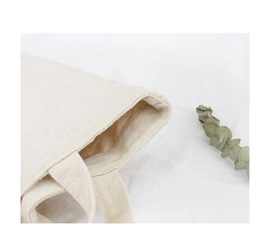 Close-up of the beige canvas tote bag showing the stitched handles and interior lining
