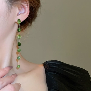Macro view of long vintage green resin bead earrings hanging on a female model
