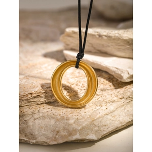 Minimalist 18k gold stainless steel round hollow pendant on black cord with stone backdrop