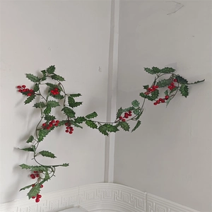 Detail of decorative Christmas garland with red berries and green leaves on a wall