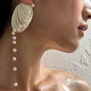 Macro detail of freshwater pearl shell earrings with long tassel on a female model