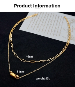 Detailed view of layered gold necklaces with screw pendant on black fabric