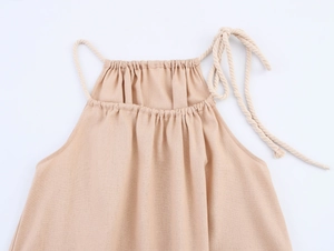 Détail de la robe en lin beige avec bretelles en corde et texture de tissu tropical