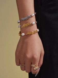 Nahaufnahme von luxuriösen Perlenarmbändern und vergoldeten Ringen an der Hand eines Modells