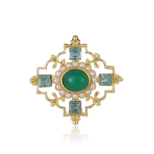 Close-up of vintage gold brooch with green gemstone, white pearls and blue crystals