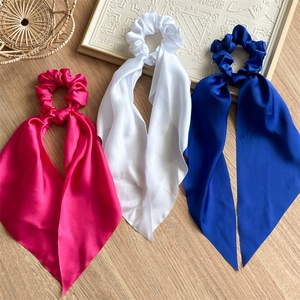 Close-up of elegant satin bow hair ties in rose pink, white, and royal blue colors