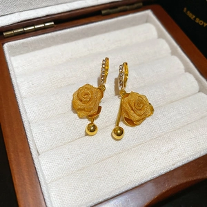 Detail of golden rose earrings with crystals on a wooden jewelry display box