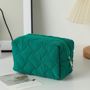 Close-up of green quilted makeup bag showing rhombus texture and silver zipper detail