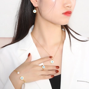 Elegant gold jewelry set with blue evil eye charms and white pearl on a model
