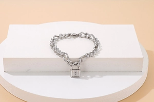 Detail eines silbernen mehrlagigen Gliederkettenarmbands mit einem Vorhängeschloss-Anhänger