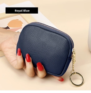 Detail of royal blue pebble leather coin purse held by hand with gold metal keychain zip