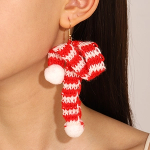 Detail of red and white striped knit earrings with soft white pom poms for Christmas