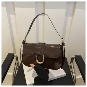 Macro detail of dark brown patent leather handbag with a golden horseshoe metal buckle