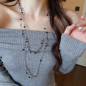 Detail of elegant multi-layer pearl flower necklace on a grey sweater