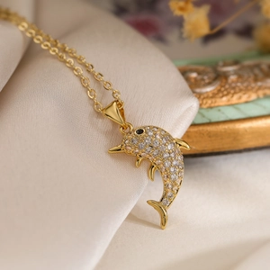Exquisite gold-plated dolphin pendant necklace with sparkling cubic zirconia on silk fabric