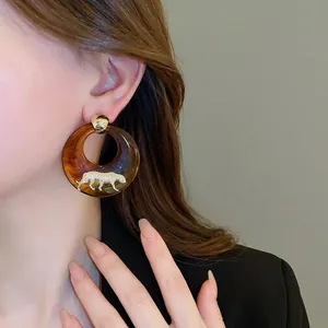 Chic tortoiseshell resin hoop earrings with a gold-tone leopard accent on a model
