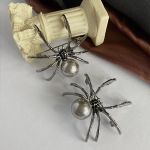 Macro shot of spider brooch with grey pearl and black rhinestones on dark metal