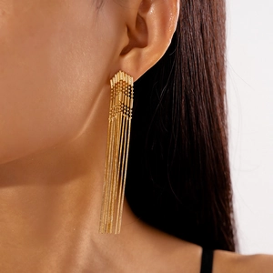 Close-up of elegant gold arrow tassel earrings with long metal chain fringe on model