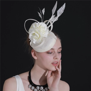 Detail view of a white bridal fascinator with mesh netting, feathers and a delicate rose flower