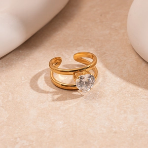 Detail of a double-layered gold ring featuring a heart-shaped zircon on a stone surface