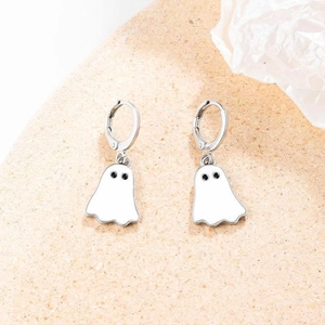 Detailed close-up of white ghost earrings with silver hoops on textured beige background