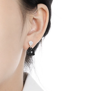 Irregular silver and black lava texture earrings with diamond inlay shown on ear