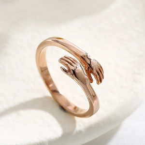 Macro shot of rose gold hugging hands ring showing intricate metal texture on stone surface