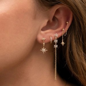 Macro shot of gold tassel earrings set with star pendants and sparkling zirconia
