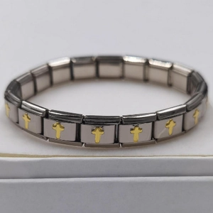 Macro detail of stainless steel modular bracelet featuring golden cross charms on silver links