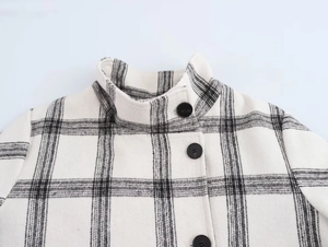 Detail shot of the stand-up collar and black buttons on a plaid wool jacket